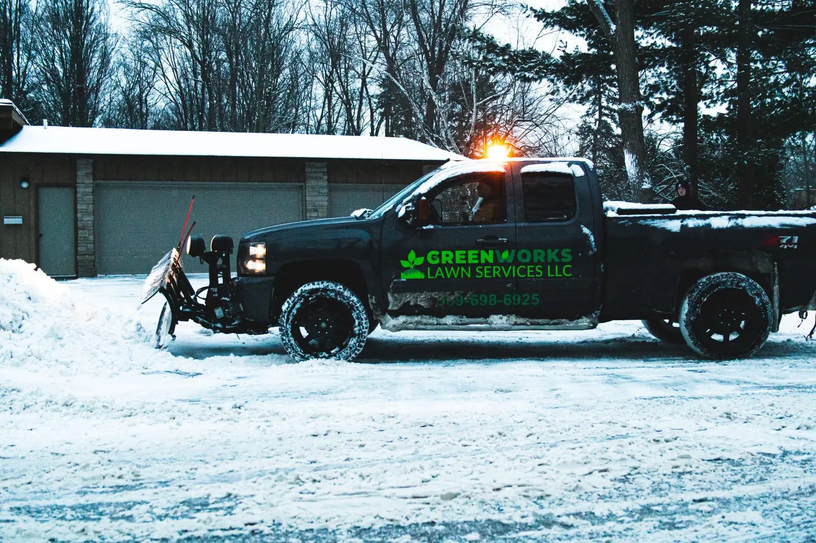 Greenworks plow truck clearing a snowy residential driveway