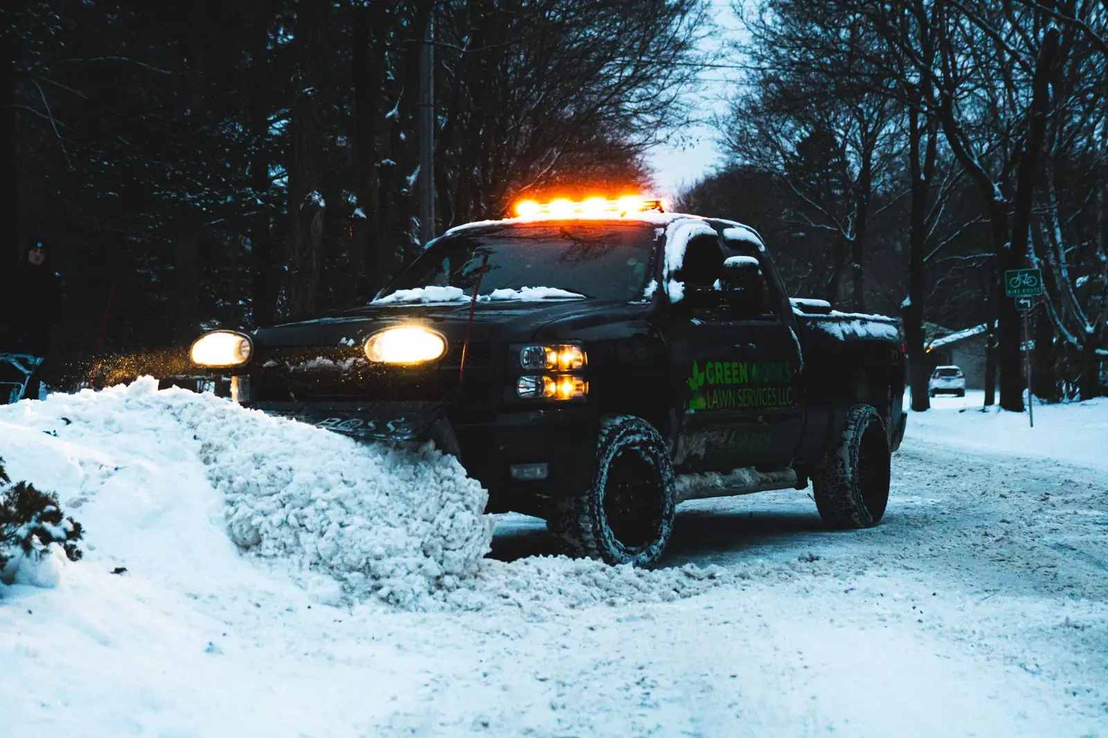 Greenworks plow truck approaching through a snowy wooded road