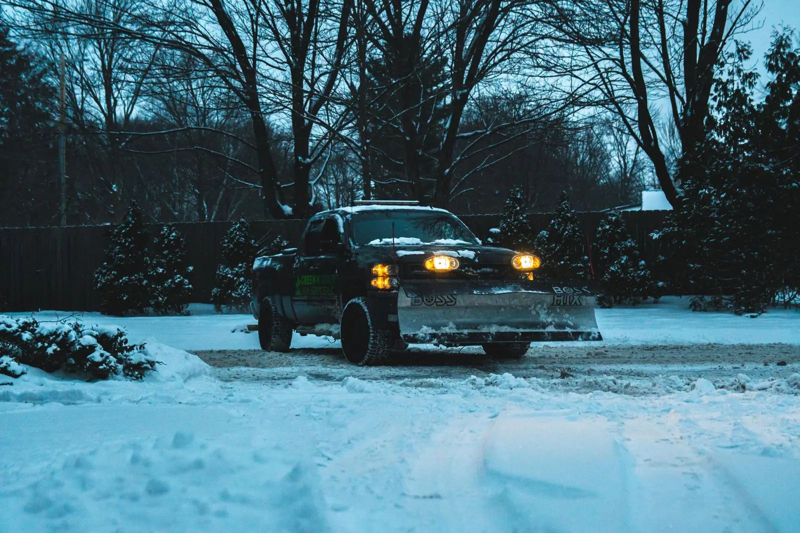 Greenworks plow truck clearing snow beside a residential property